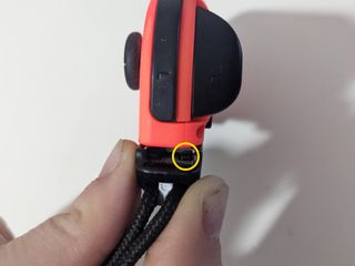 How to remove a stuck Joy-Con strap: place flat object between the Joy-Con body and strap where the prongs are seen