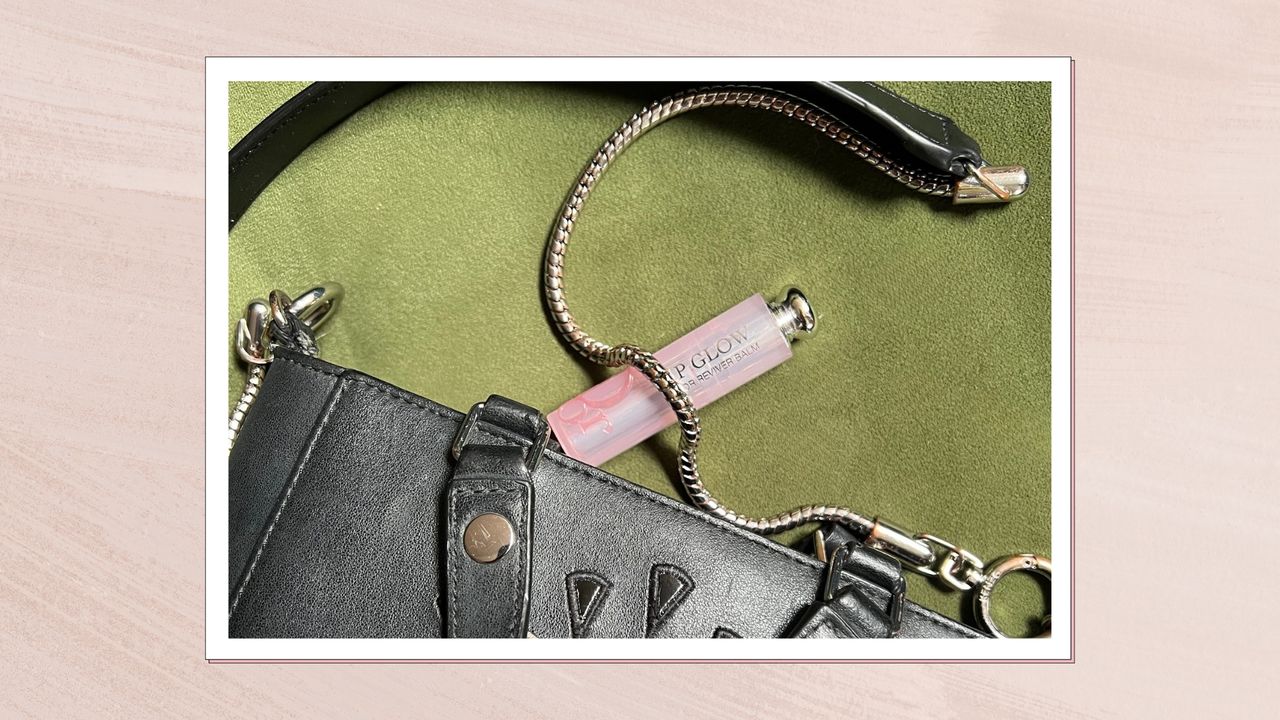 A close up of Digital Beauty Editor, Fiona McKim&#039;s handbag, laid on a green velvet background with a pink tube of Dior&#039;s Lip Glow visible - with a silver chain resting across it/ features in a pastel pink template