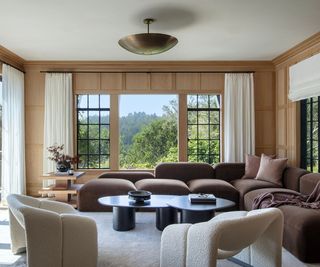 Wooden panelled living room with brown couch and cream armchairs