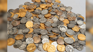 Pile of over 400 gold and silver coins from the 1st century AD, against a light grey background