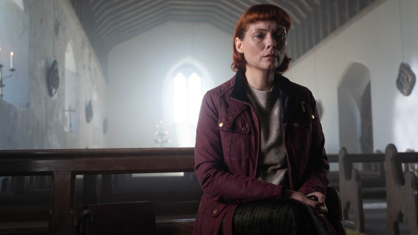 Melinda sitting in a church looking sad and wearing a dark red jacket 