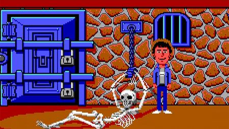 '80s adventure game Maniac Mansion with a man standing and smiling next to a skeleton chained to a wall