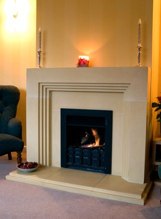 art deco fireplace in a light stone with lit fire