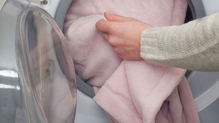 how to wash an electric blanket - woman putting electric blanket in washing machine - dreamland