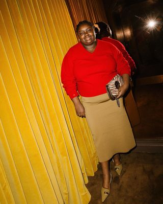 woman in red sweater and beige skirt