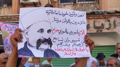 Protesters in Syria hold posters depicting President Bashar al-Assad
