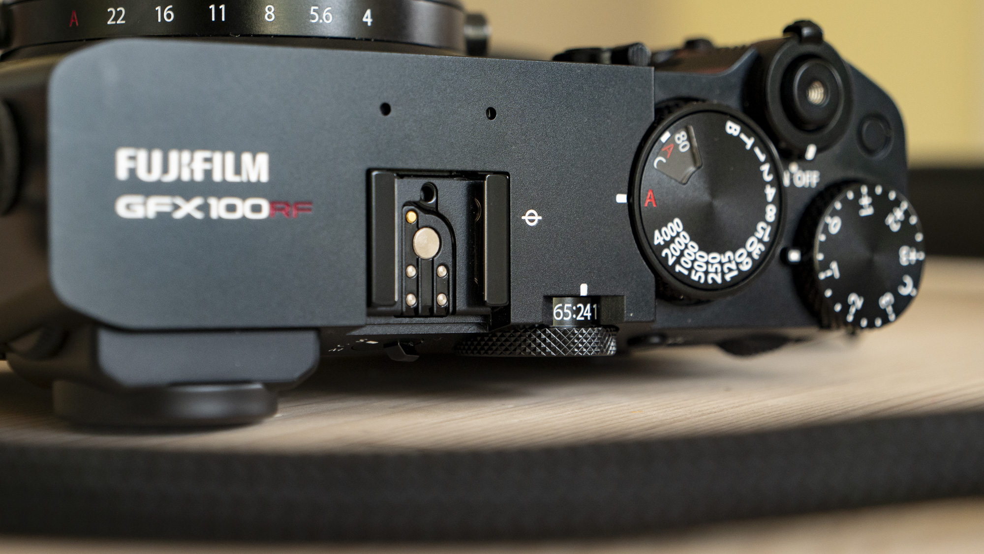 All-black Fujifilm GFX100RF rangefinder-style camera on a wooden table