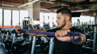 Man warming up in gym with band shoulder dislocate