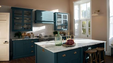 A bright teal and pink kitchen with a marble countertop island and brass details