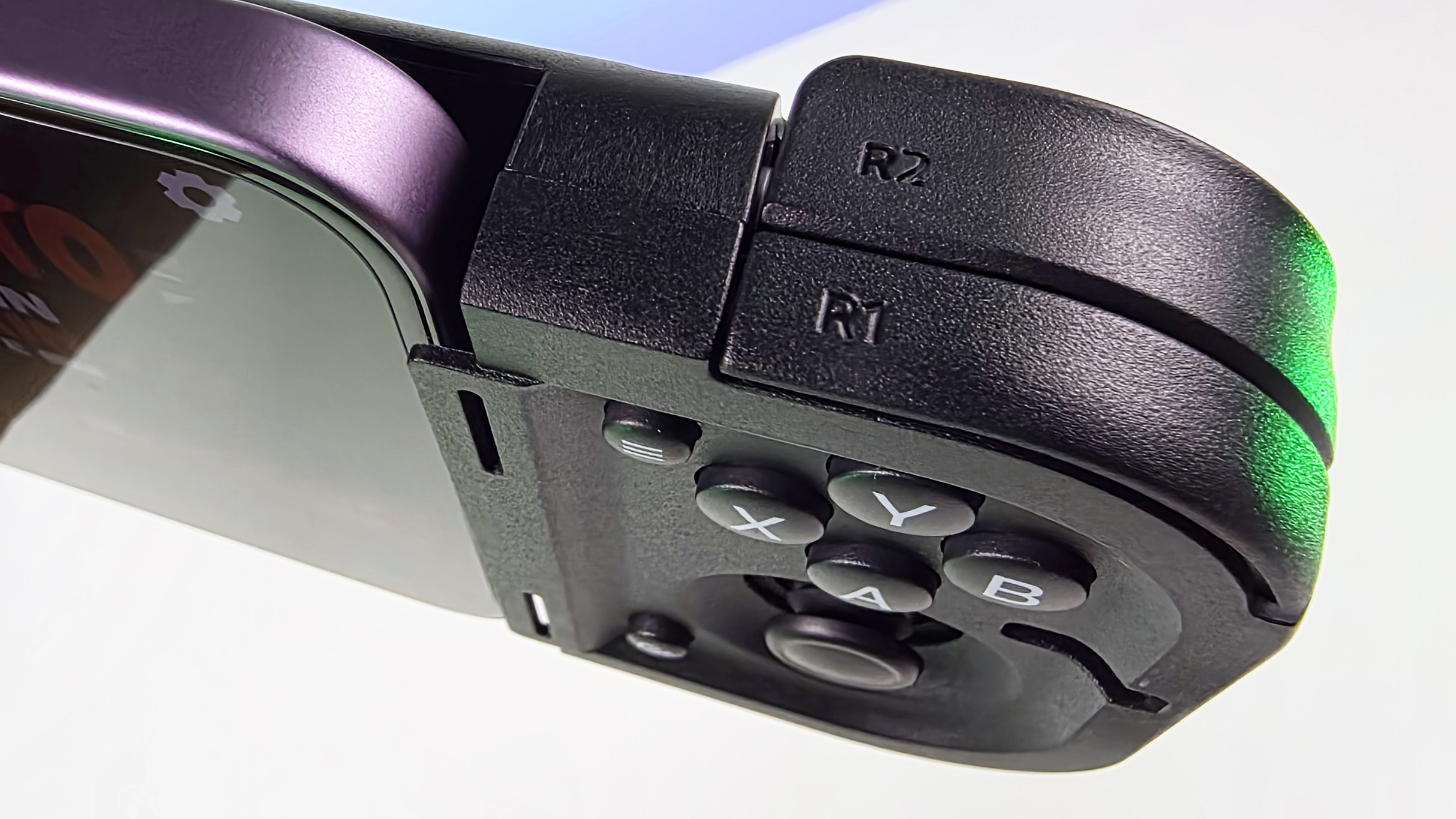 Close-up of the Razer Prio right controller module attached to a purple phone, showing R1/R2 shoulder triggers, ABXY face buttons, and an analog thumbstick.