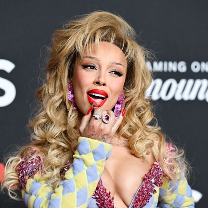 a woman with blonde hair applying bright red lipstick