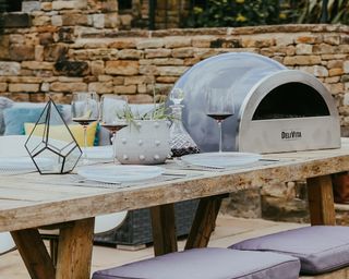 Tabletop pizza oven on a rustic outdoor wooden table