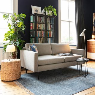 wooden floor living room with a book shelf cabinet and a grey sofa with minimalistic décor