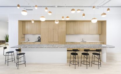 A minimalist kitchen with flat wooden cabinets and pendant lights