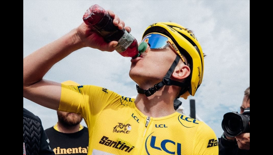 Tadej Pogacar, in the yellow jerse, drinks a red chery juice drink