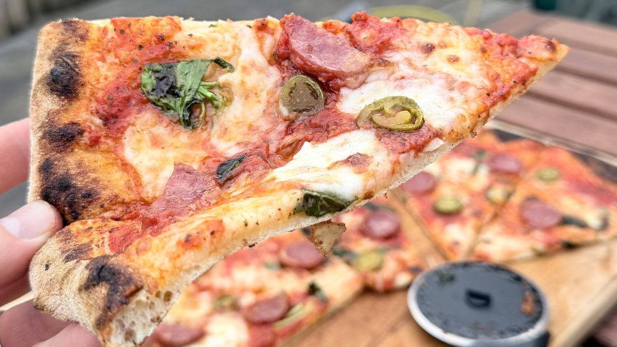A slice of pizza in hand, the pizza was cooked on the Gozney Arc XL