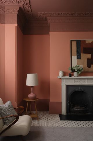 coral living room with darker ceiling and woodwork, tiled floor, fireplace, artwork, lamp, retro armchair