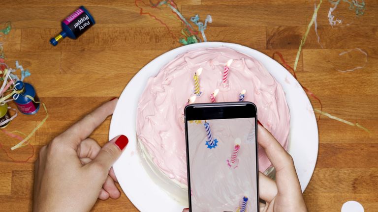 Taking picture with phone of cake with candles