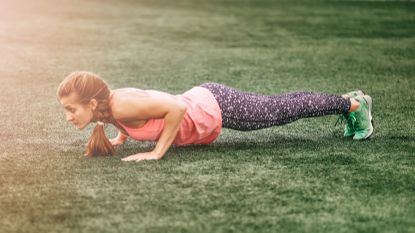 Woman doing burpees on field