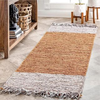 A white and natural colored woven leather rug sits on a light floor