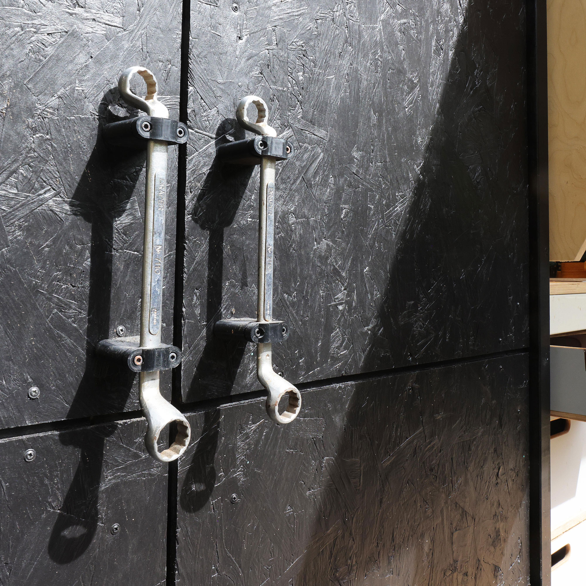 Cuprinol shed of the year in black with spanner handles and wooden workshop desk hidden inside
