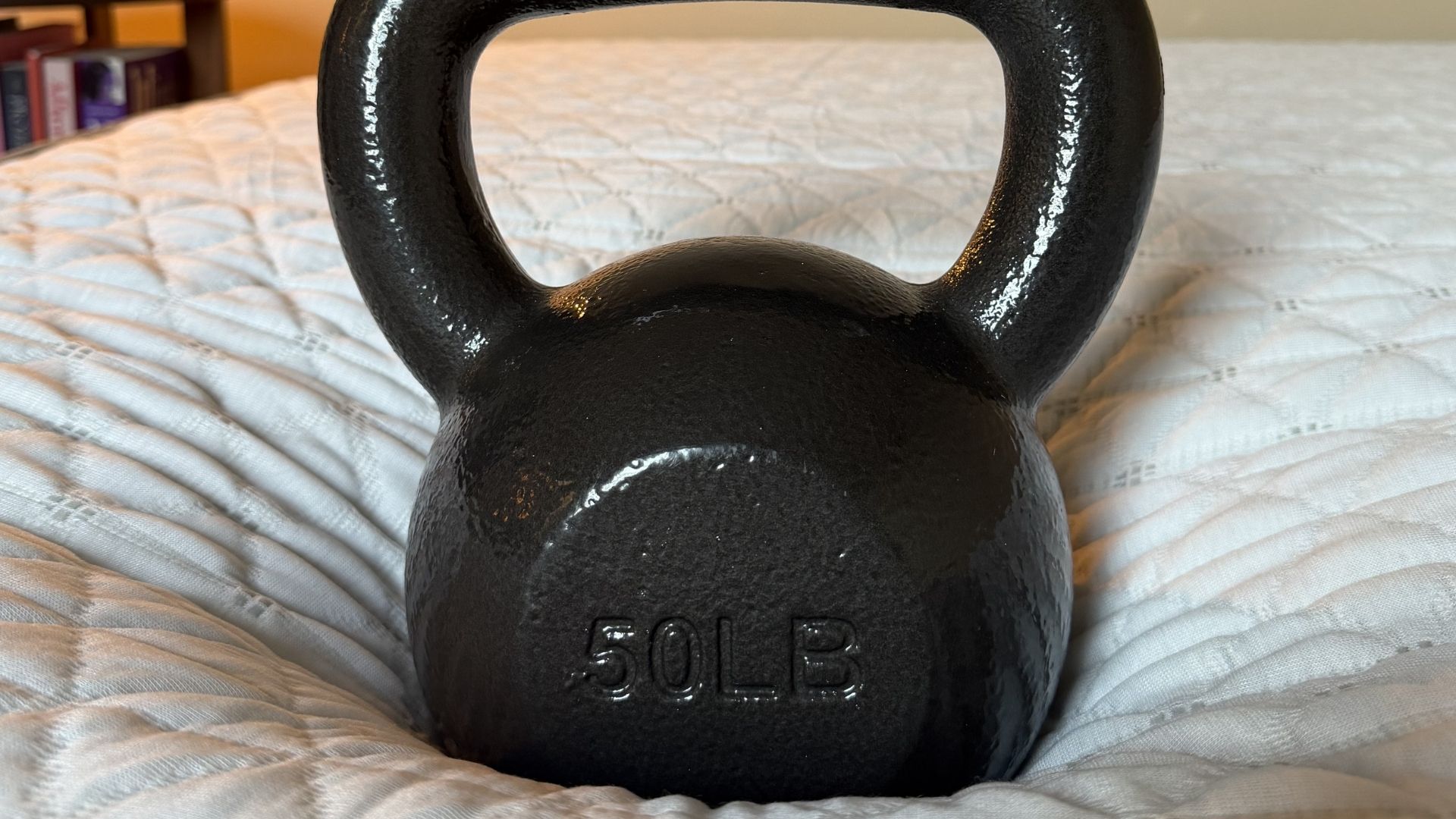 The image shows a 50lb weight placed on the side of a mattress in order to test its edge support