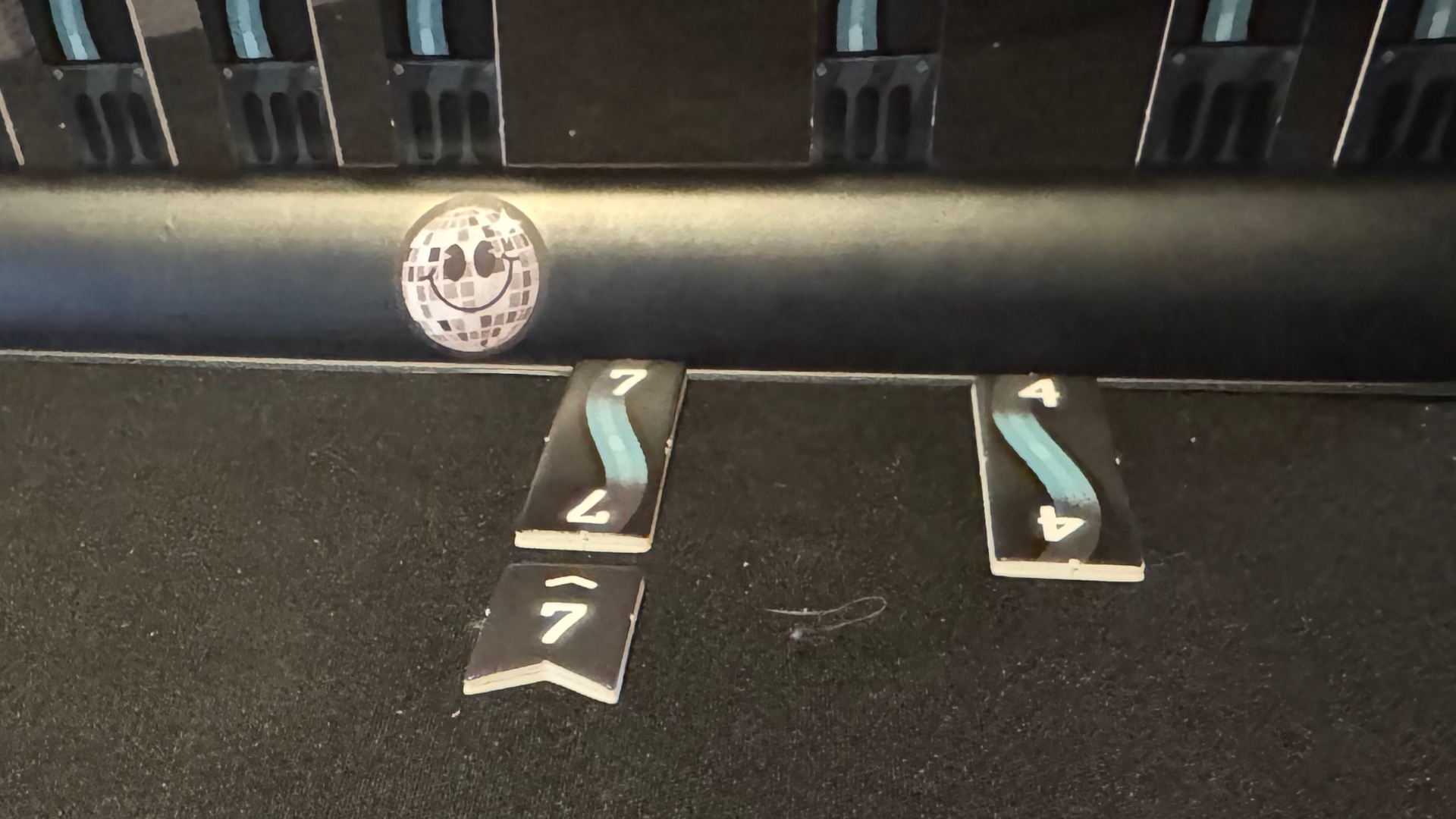 A smiley face on a black holder, with tokens below it on a black surface