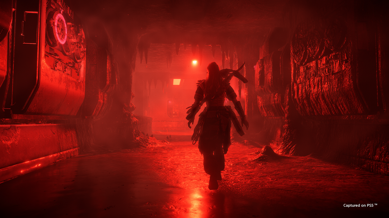 Aloy walks down a corridor draped in red in Horizon Forbidden West