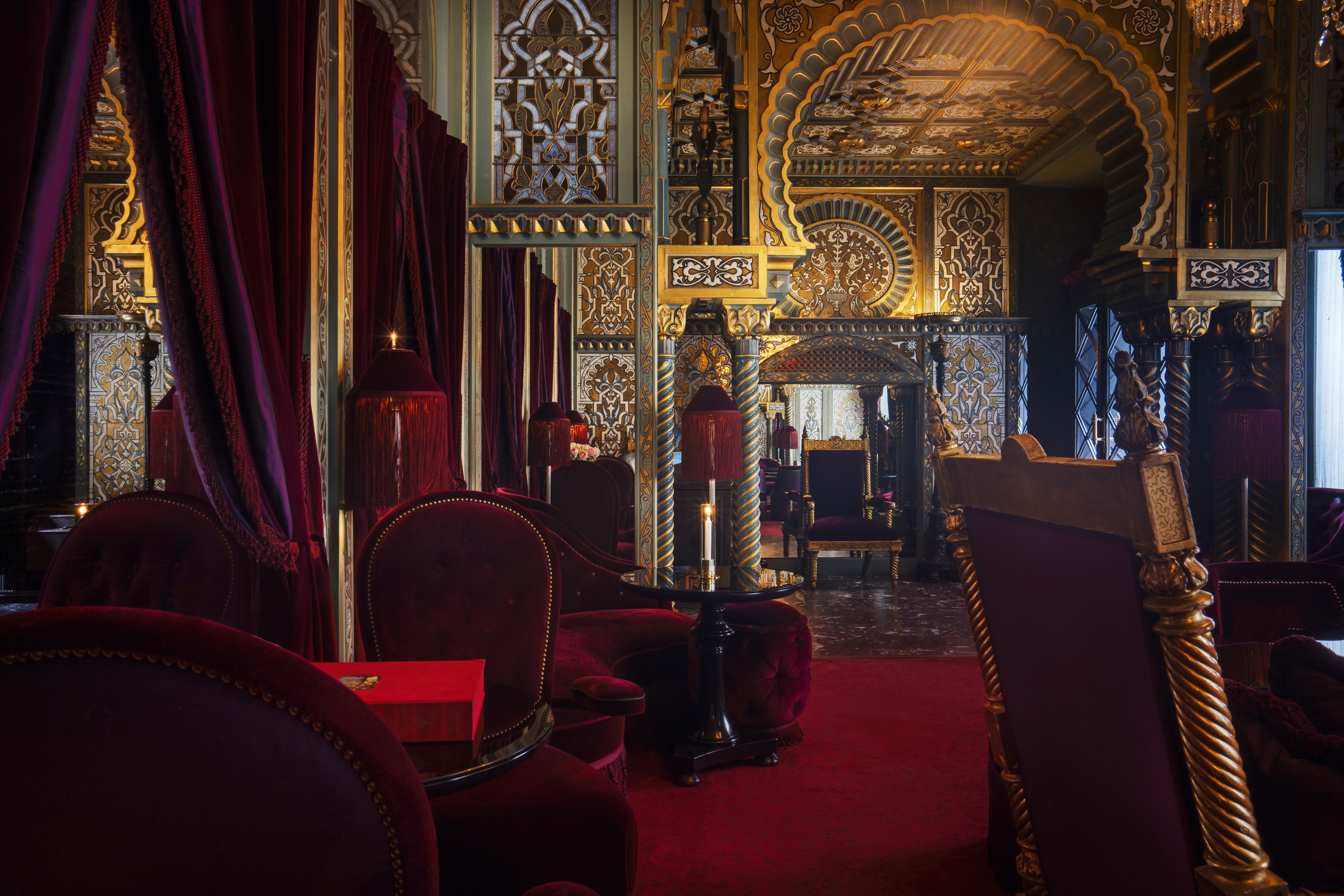 a plush hotel with red velvet chairs, red carpets, and a decorative ceiling