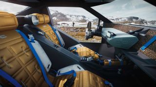 View from car interior looking out to mountain with gold padded chairs and blue double seatbelts.