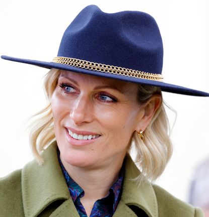 Zara Tindall wearing a blue hat and green coat looking to the side