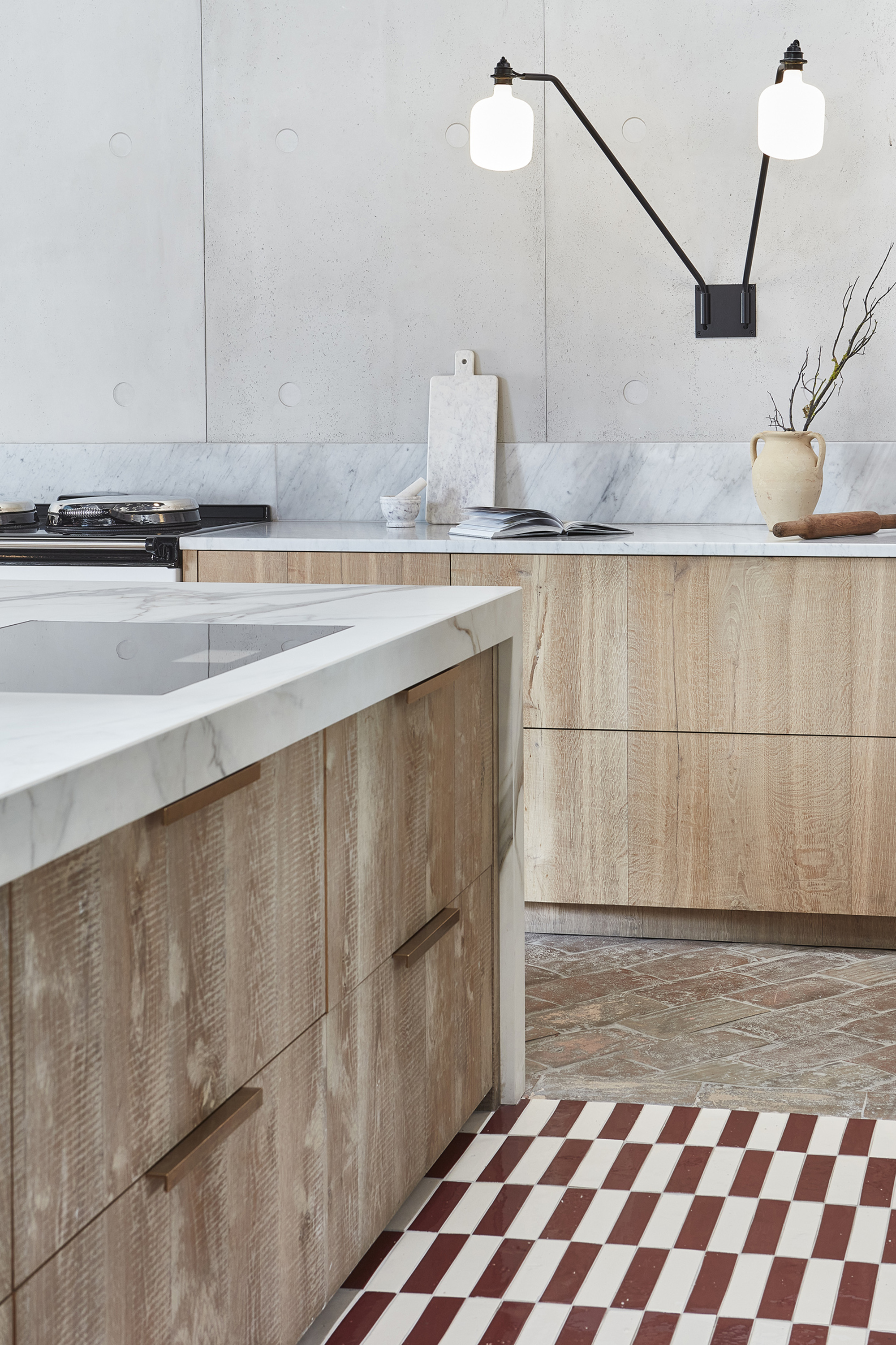 A modern kitchen with wooden slab cabinets, marble countertops, and rectangular checherboard style flooring