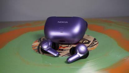 The Nokia Clarity Earbuds 2 + in So Purple on a green and orange record