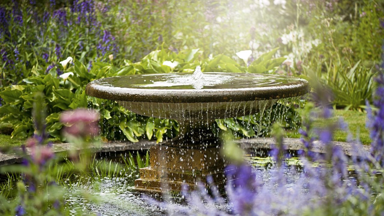 Beautiful summer garden with water fountain in amongst the flowers