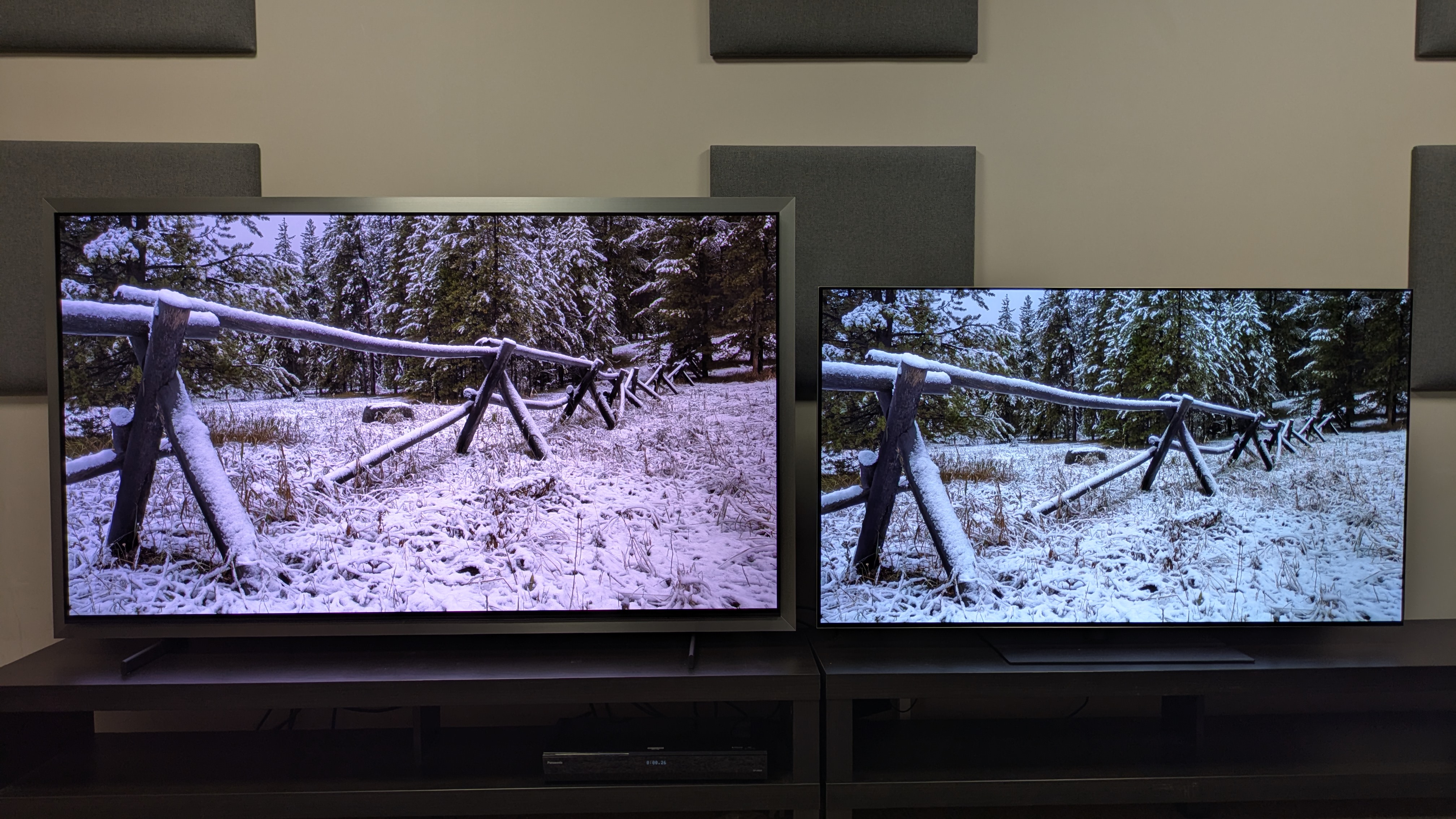 Samsung S99H (left) vs LG G6 (right) showing a snow-covered fence on screen. Both TVs show good brightness with brilliant whites, but the G6 has the edge in peak areas