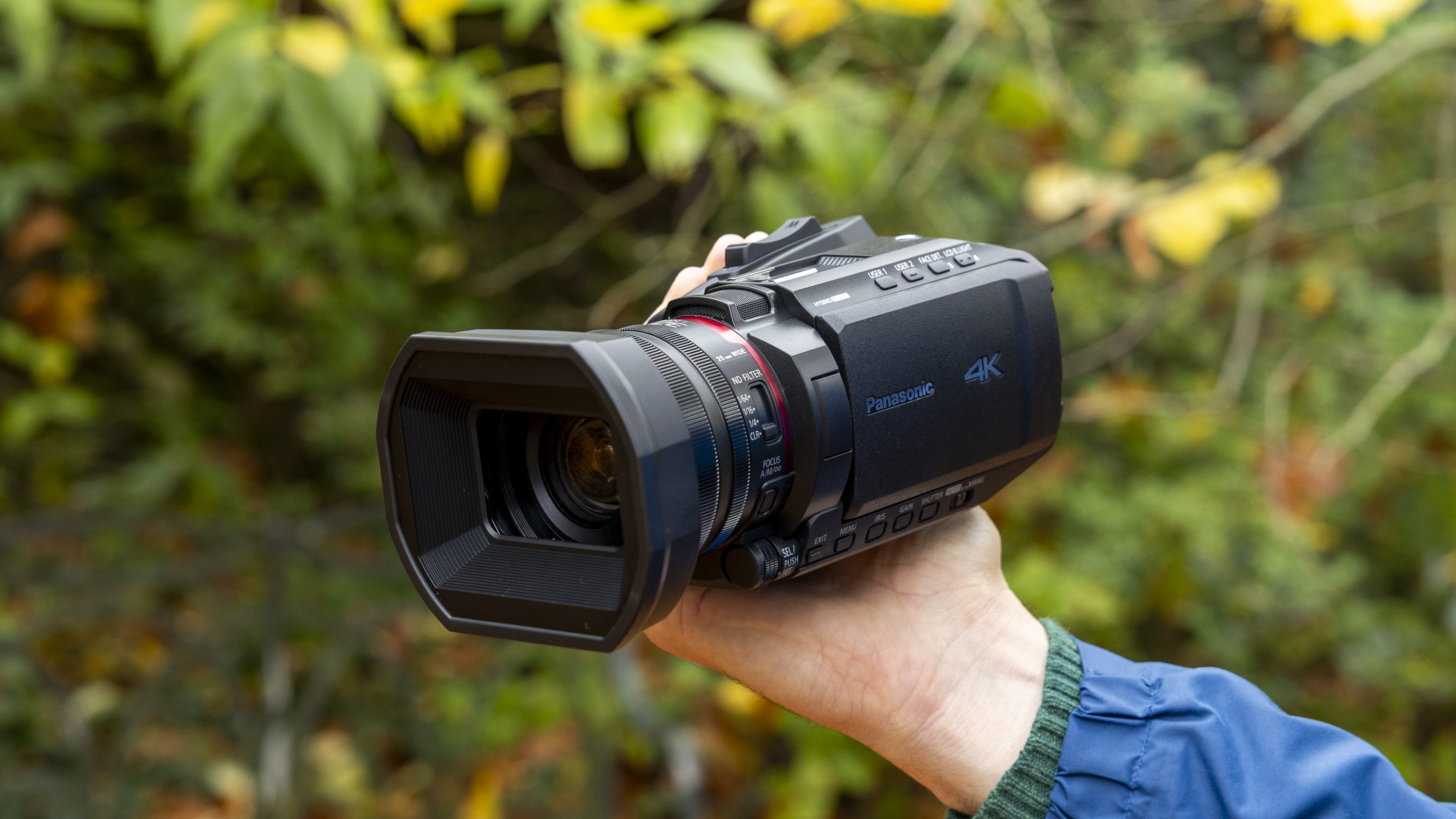 The Panasonic HC-X1200 camcorder held by a female photographer against an orange autumnal backdrop
