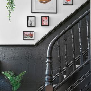 a monochrome stairwell with black textured wallpaper and white walls and framed wall art