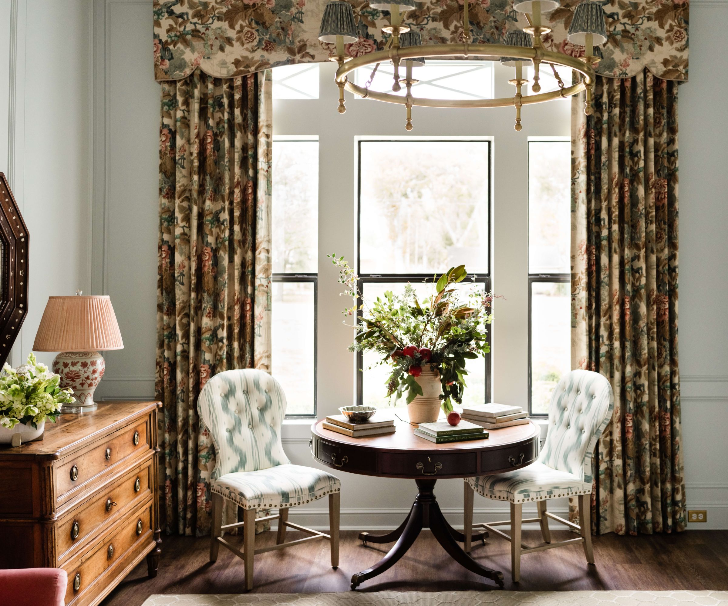 pale green study home office with moldings and antique furniture including antique table, chairs, and dresser with floral curtains