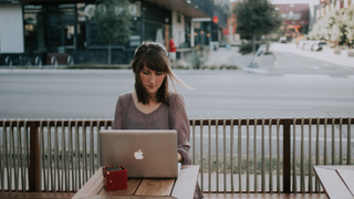 Woman sat alone outside with laptop