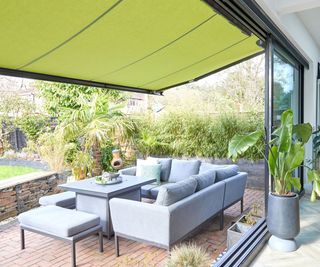 Thomas Sanderson awning in collaboration with influencer Kelly Anderson. A bright green material awning pulled out over a patio in front of bifold doors