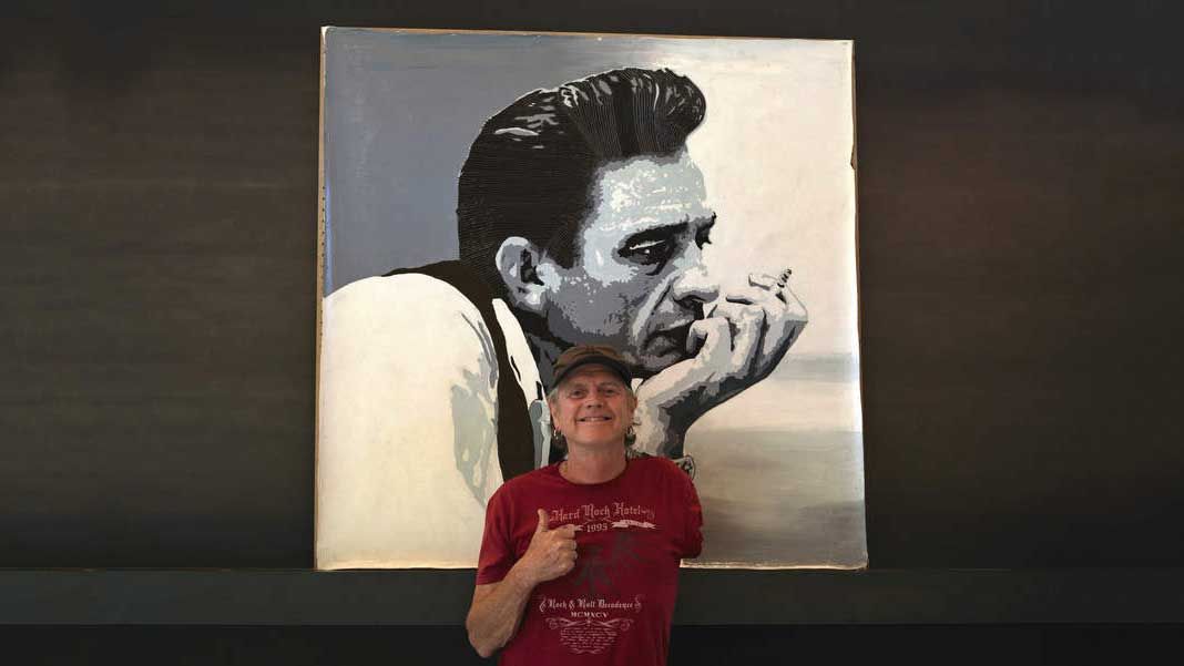 Rick Allen standing in front of a portrait of Johnny Cash