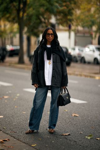 woman wearing fringe jacket, white t shirt, cardigan, baggy jeans and heels