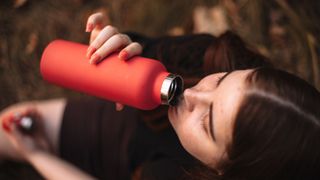 Woman drinking from stainless steel water tank