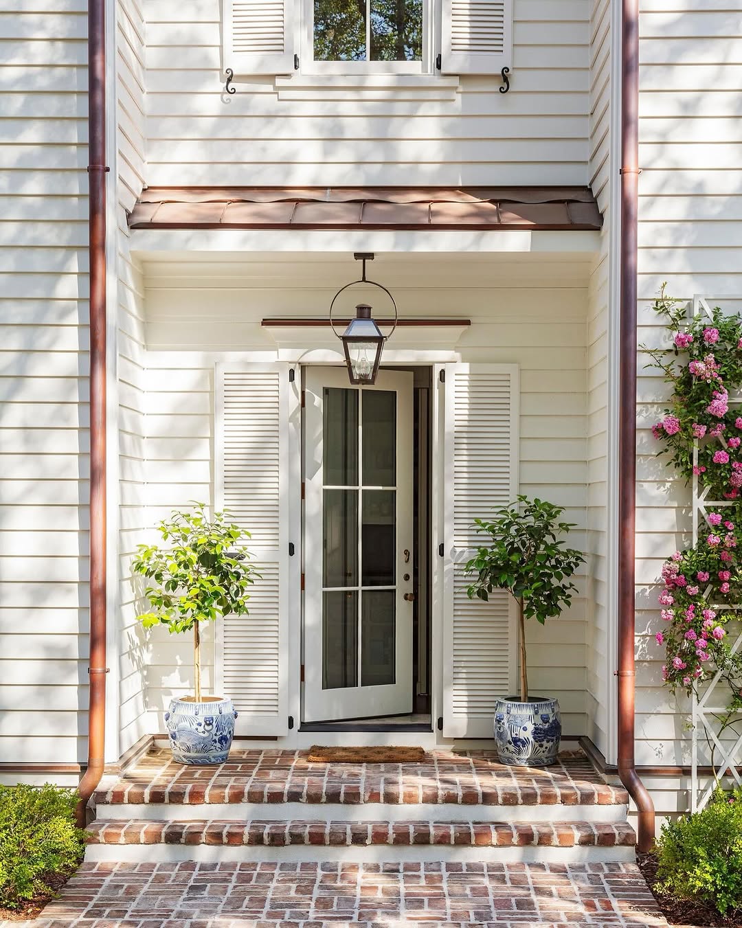 White 6 light modern front door on a white traditional home with brick walkways