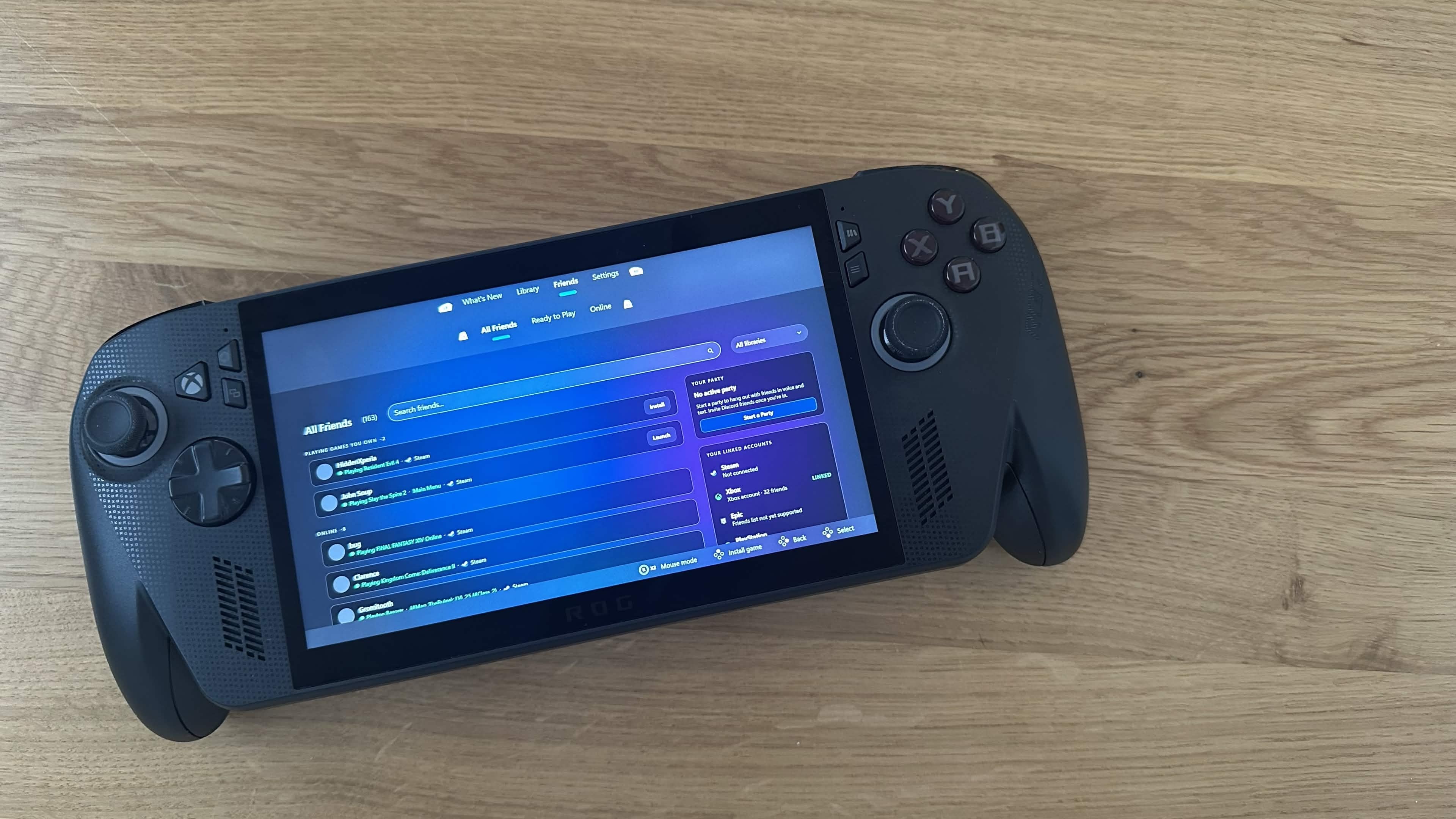 ASUS ROG Ally running Winhanced friends menu with Xbox-style interface displayed on a wooden table.