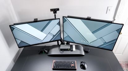 An overhead view of a dual-monitor desk setup with the SmallRig Camera Desk Mount holding up a webcam behind the displays