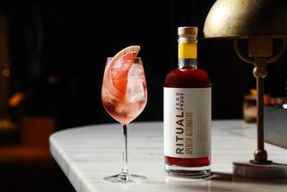 a bottle of Ritual Aperitif with a wine glass loaded with ice and garnishes