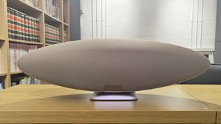 Bowers & Wilkins Zeppelin Pro Edition wireless speaker on wooden table with bookcase in background