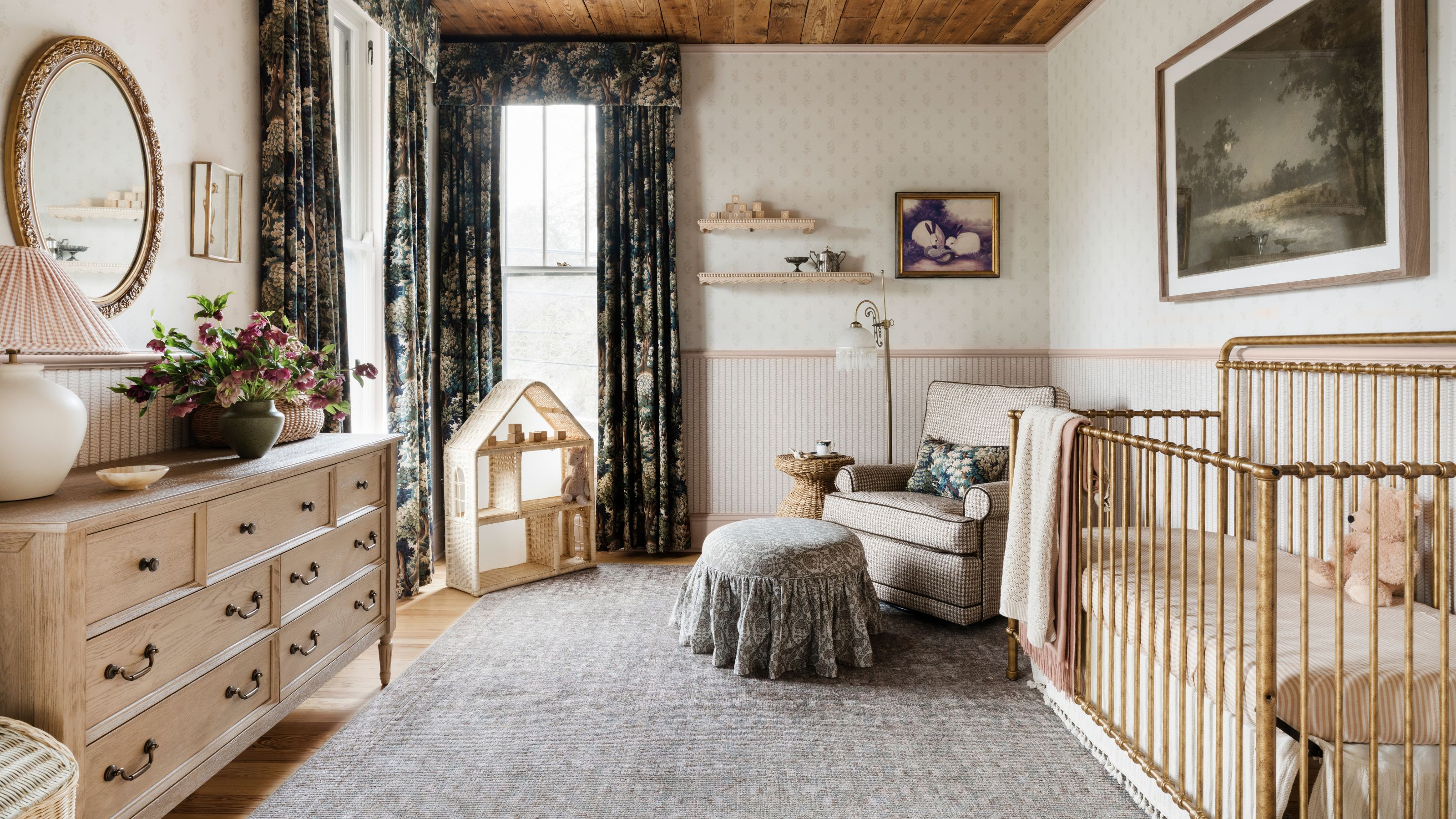 a layered vintage style nursery room with both a floral and stripe wallpaper, crib, floral drapes and layered patterns and decor