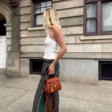 Influencer @meganadelaide wears a white vest top with baggy track pants in dark green.